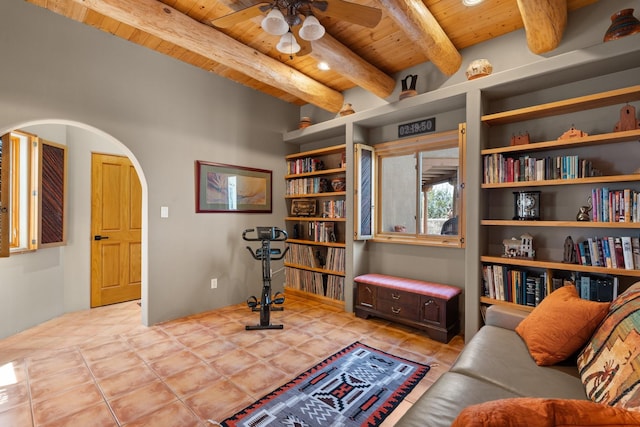 living area with beam ceiling, arched walkways, ceiling fan, tile patterned flooring, and wooden ceiling