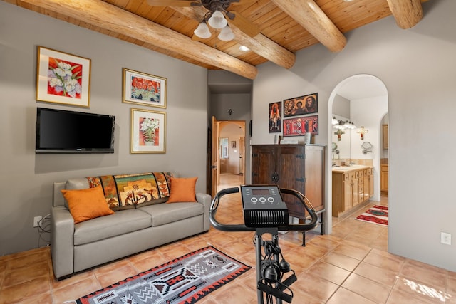 living room featuring ceiling fan, beamed ceiling, light tile patterned floors, wooden ceiling, and arched walkways