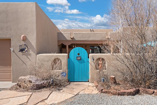 entrance to property featuring an attached garage, fence, and a gate