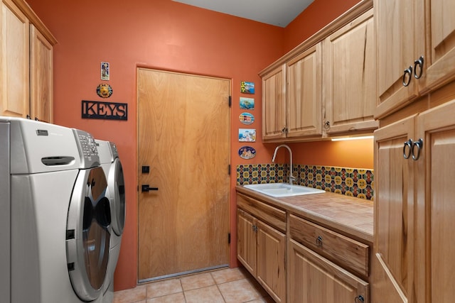 laundry room with washing machine and clothes dryer, light tile patterned floors, cabinet space, and a sink