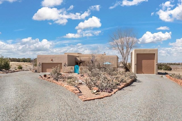 pueblo-style house with a garage, driveway, and stucco siding