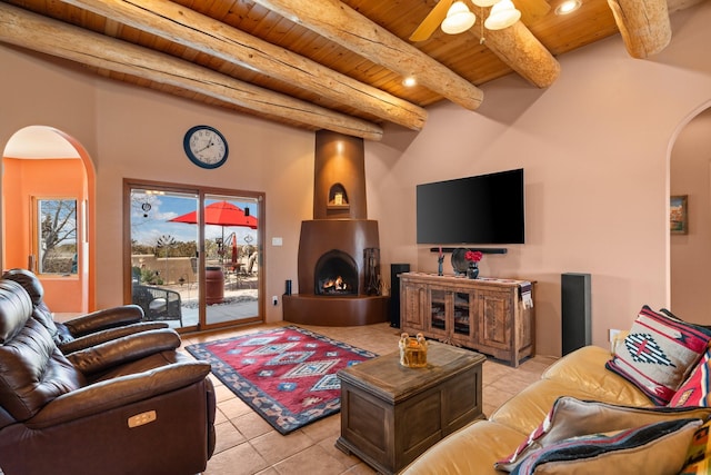 living area featuring beamed ceiling, a large fireplace, arched walkways, wooden ceiling, and light tile patterned flooring