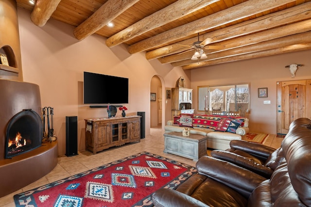 living room with tile patterned flooring, a lit fireplace, wooden ceiling, arched walkways, and a ceiling fan