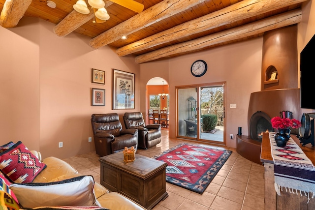 living room with light tile patterned floors, a ceiling fan, arched walkways, wooden ceiling, and beamed ceiling