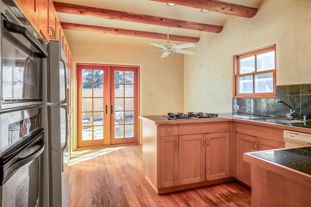 kitchen featuring beam ceiling, a sink, a peninsula, decorative backsplash, and stainless steel gas cooktop