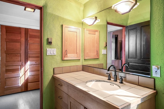 bathroom with vanity, wood finished floors, and a textured wall