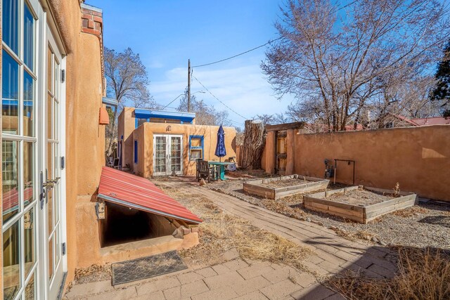 view of patio featuring an outbuilding, french doors, fence, and a garden