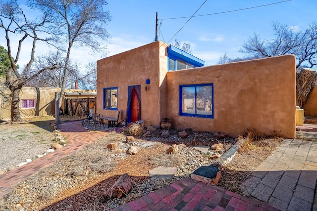 view of front facade featuring a patio area, fence, and stucco siding