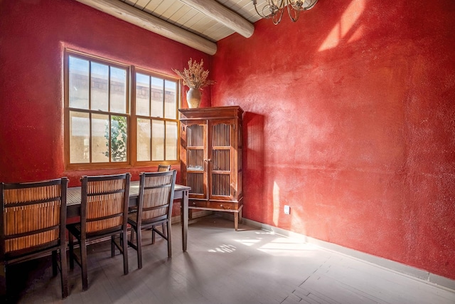 dining area with wooden ceiling, beamed ceiling, and a textured wall