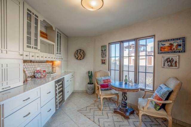 kitchen featuring light tile patterned floors, light countertops, wine cooler, white cabinets, and glass insert cabinets