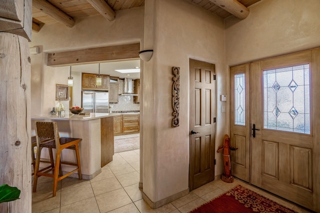 foyer entrance featuring beamed ceiling, light tile patterned floors, and wood ceiling