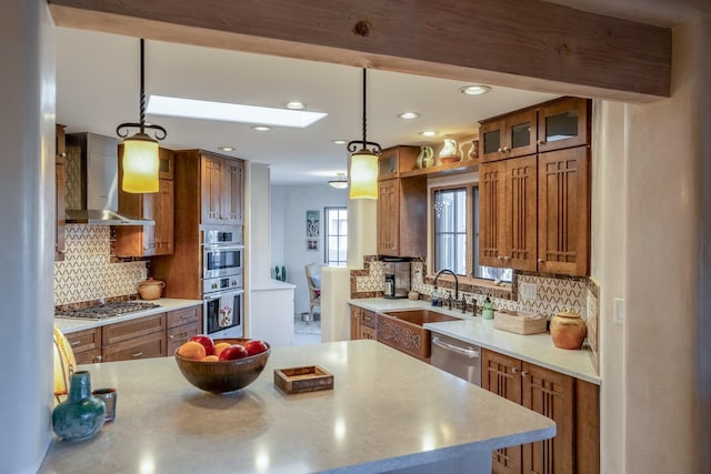 kitchen with a sink, brown cabinets, appliances with stainless steel finishes, and wall chimney exhaust hood