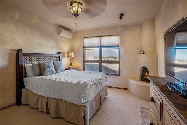 bedroom featuring a wall mounted air conditioner, a large fireplace, baseboards, light colored carpet, and ceiling fan