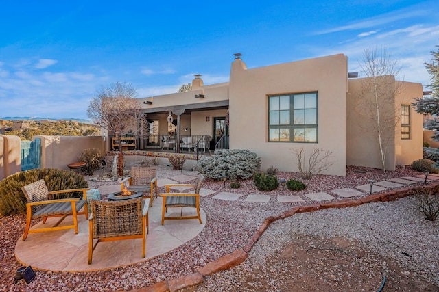 back of house featuring stucco siding, a fire pit, a patio, and fence