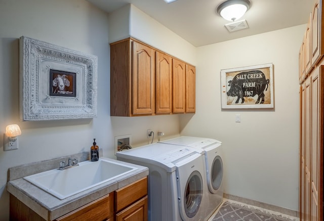 washroom featuring baseboards, visible vents, cabinet space, a sink, and independent washer and dryer