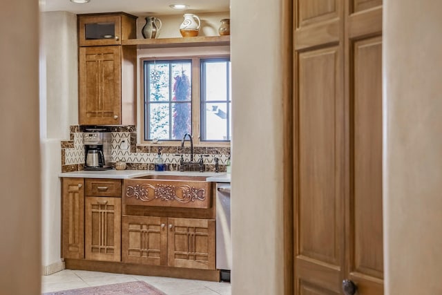 bar with a sink, backsplash, stainless steel dishwasher, and light tile patterned flooring