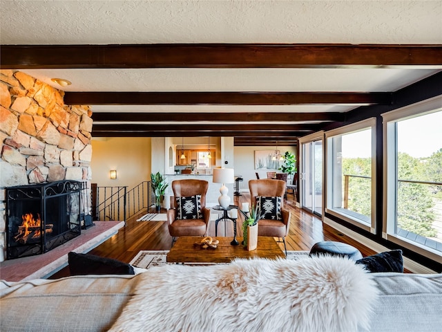 living room with beam ceiling, wood finished floors, a fireplace, and a textured ceiling