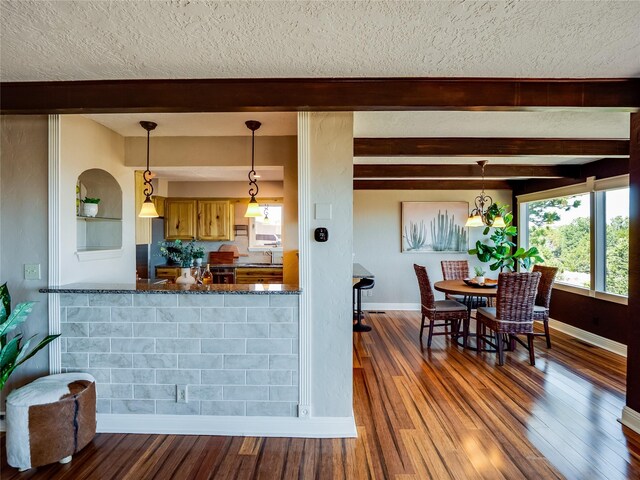 kitchen featuring dark wood-style floors, beamed ceiling, a textured ceiling, and baseboards