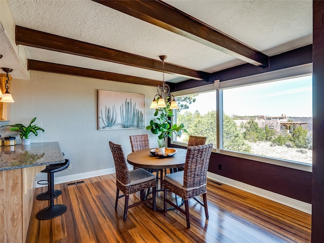 dining room with beamed ceiling, dark wood-type flooring, a notable chandelier, a textured ceiling, and baseboards