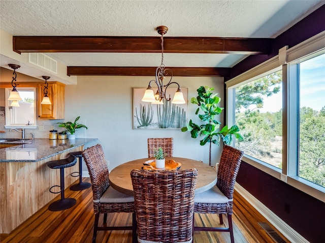 dining room featuring visible vents, beam ceiling, a textured ceiling, and hardwood / wood-style flooring