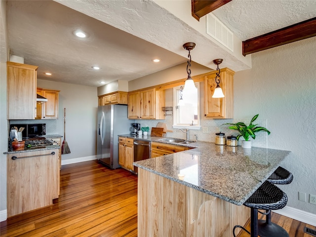 kitchen with visible vents, a breakfast bar area, a peninsula, stainless steel appliances, and a sink