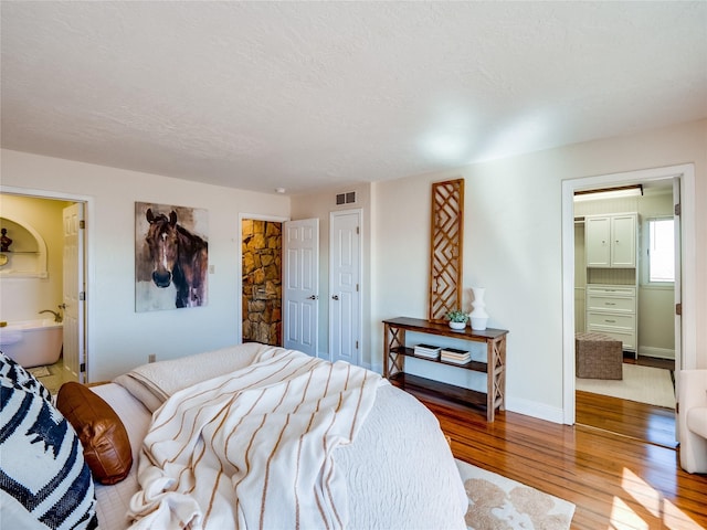 bedroom with visible vents, a walk in closet, wood finished floors, a closet, and a textured ceiling