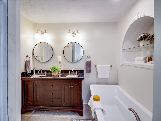 bathroom with a textured ceiling, a soaking tub, double vanity, and a sink