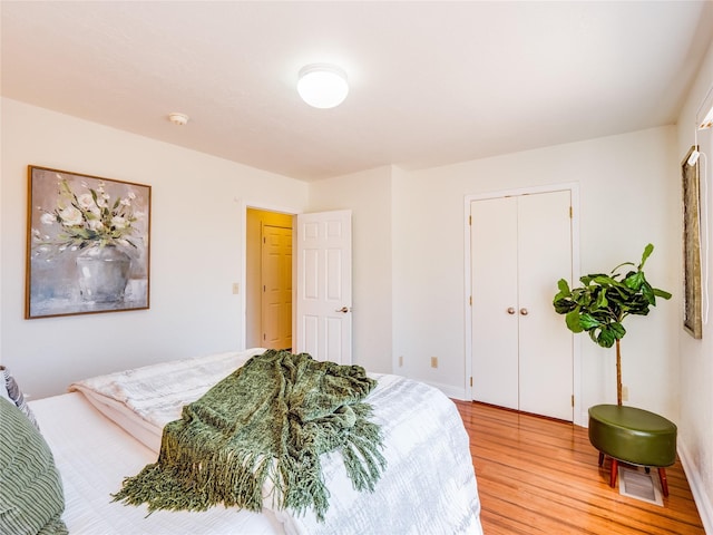 bedroom with a closet, visible vents, and light wood finished floors