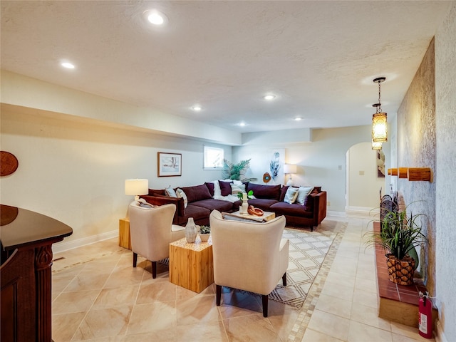 living room featuring a textured ceiling, recessed lighting, arched walkways, light tile patterned floors, and baseboards