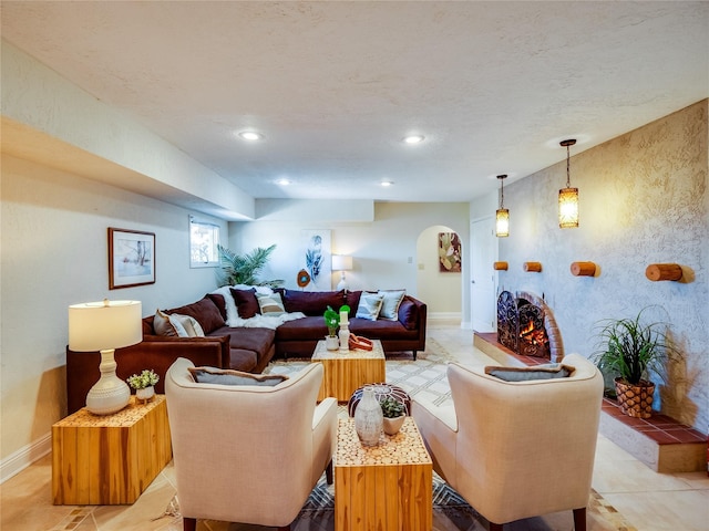 living room with recessed lighting, arched walkways, a warm lit fireplace, and baseboards