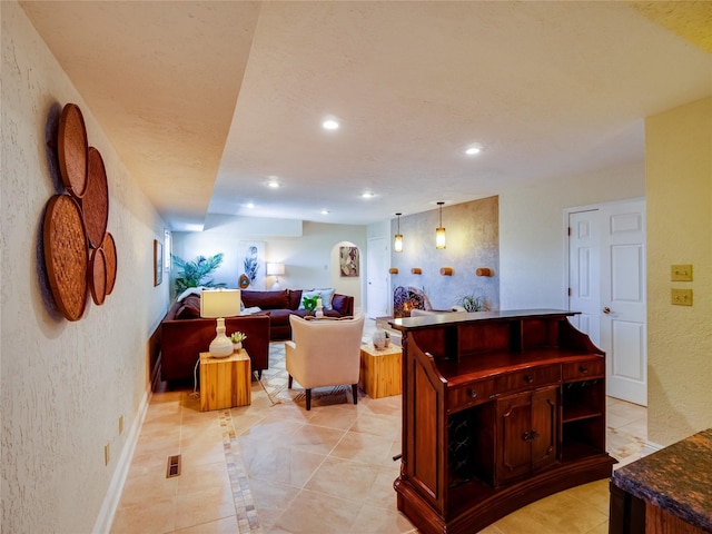 living area with visible vents, baseboards, light tile patterned flooring, recessed lighting, and a textured wall