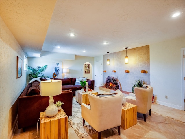 living area featuring recessed lighting, baseboards, a lit fireplace, and a textured wall