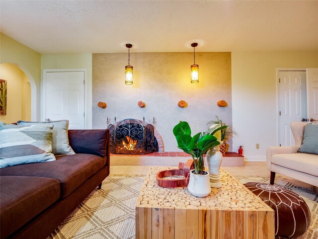 living area featuring arched walkways, a warm lit fireplace, and baseboards