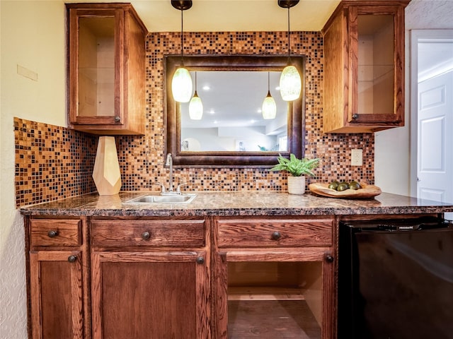 kitchen with a sink, decorative backsplash, dark countertops, and brown cabinetry