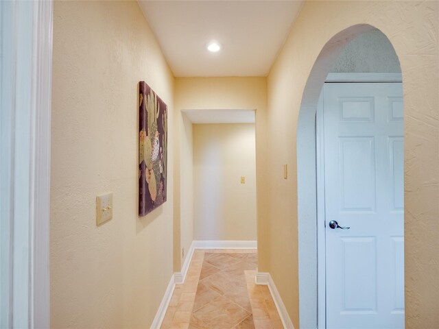 hallway featuring arched walkways and baseboards