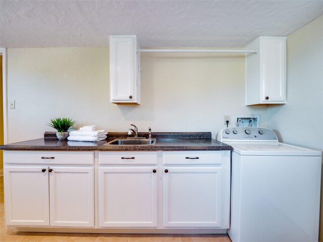 laundry room featuring a textured ceiling, washer / dryer, cabinet space, and a sink