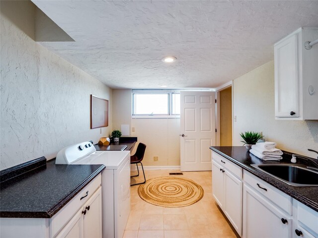 laundry room with washer / dryer, a textured wall, light tile patterned flooring, a textured ceiling, and a sink