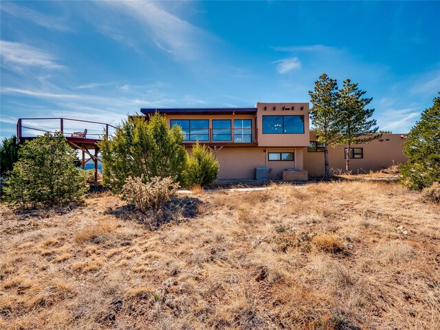 back of property with stucco siding and cooling unit