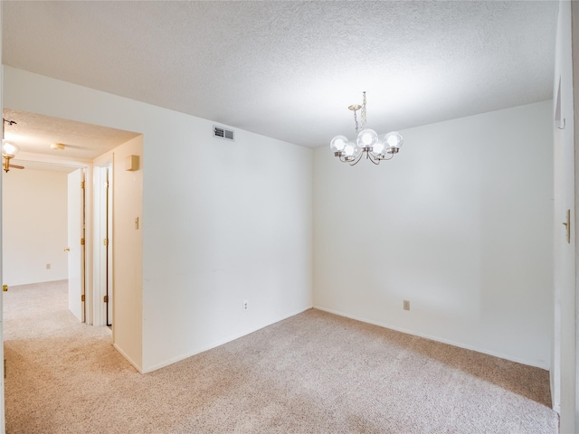 spare room featuring carpet flooring, visible vents, a chandelier, and a textured ceiling