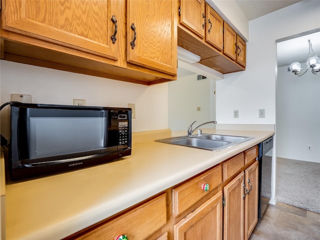 kitchen with brown cabinets, black appliances, a sink, an inviting chandelier, and light countertops