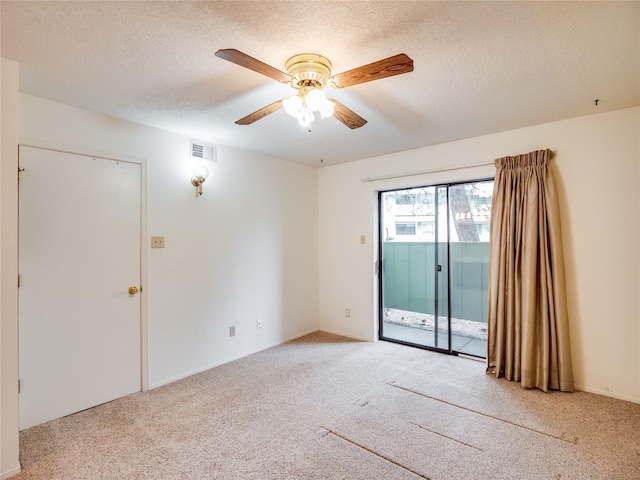 empty room with a textured ceiling, a ceiling fan, visible vents, and light carpet