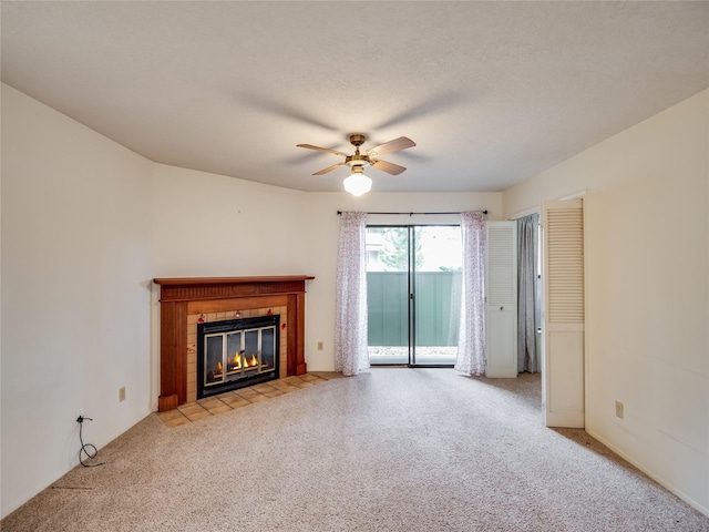 unfurnished living room with a textured ceiling, light colored carpet, ceiling fan, and a tile fireplace