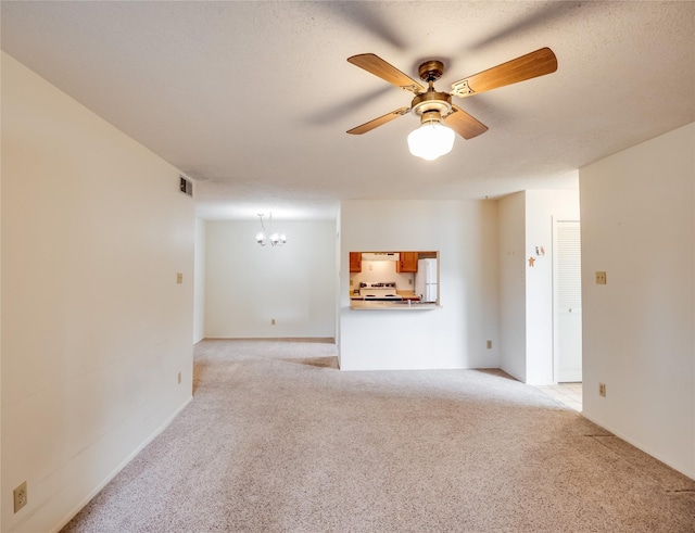 unfurnished living room with light carpet, visible vents, ceiling fan with notable chandelier, and a textured ceiling