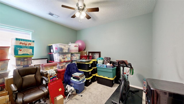 interior space with visible vents, a textured ceiling, carpet, baseboards, and ceiling fan