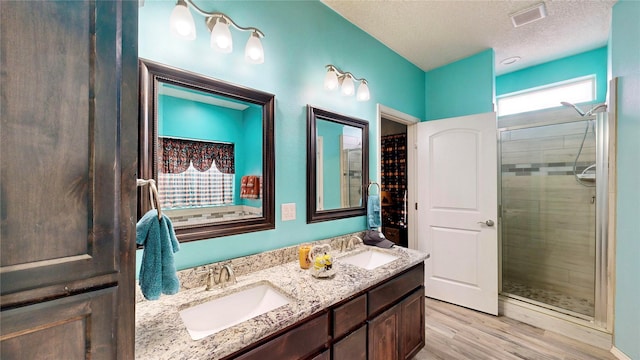 bathroom featuring a shower stall, a textured ceiling, wood finished floors, and a sink