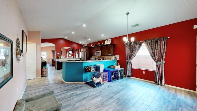 kitchen featuring a notable chandelier, stainless steel appliances, arched walkways, light countertops, and lofted ceiling