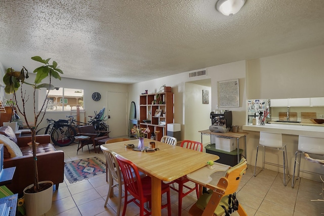 dining space with light tile patterned floors, visible vents, and a textured ceiling