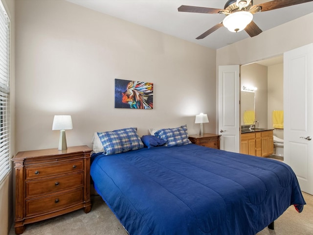 bedroom with a ceiling fan, light colored carpet, and ensuite bathroom
