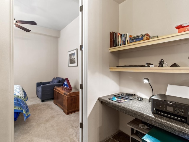 carpeted office space with a ceiling fan and built in study area