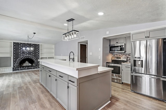 kitchen with lofted ceiling, light wood finished floors, gray cabinets, and appliances with stainless steel finishes